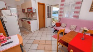 A compact living space with a kitchenette, a dining area, and a sofa. - Apartments Sopic (Rogoznica)