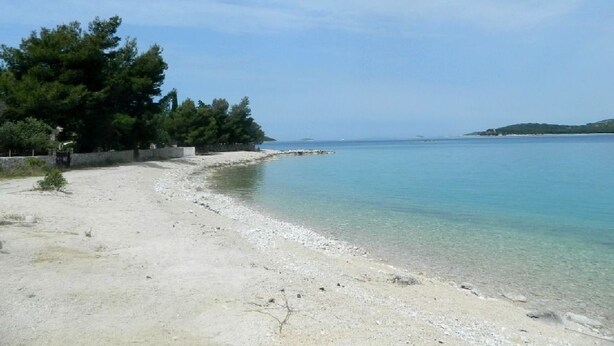 A beach with clear water, a sandy shore, and trees in the background. - Apartments Mirta (Razanj)