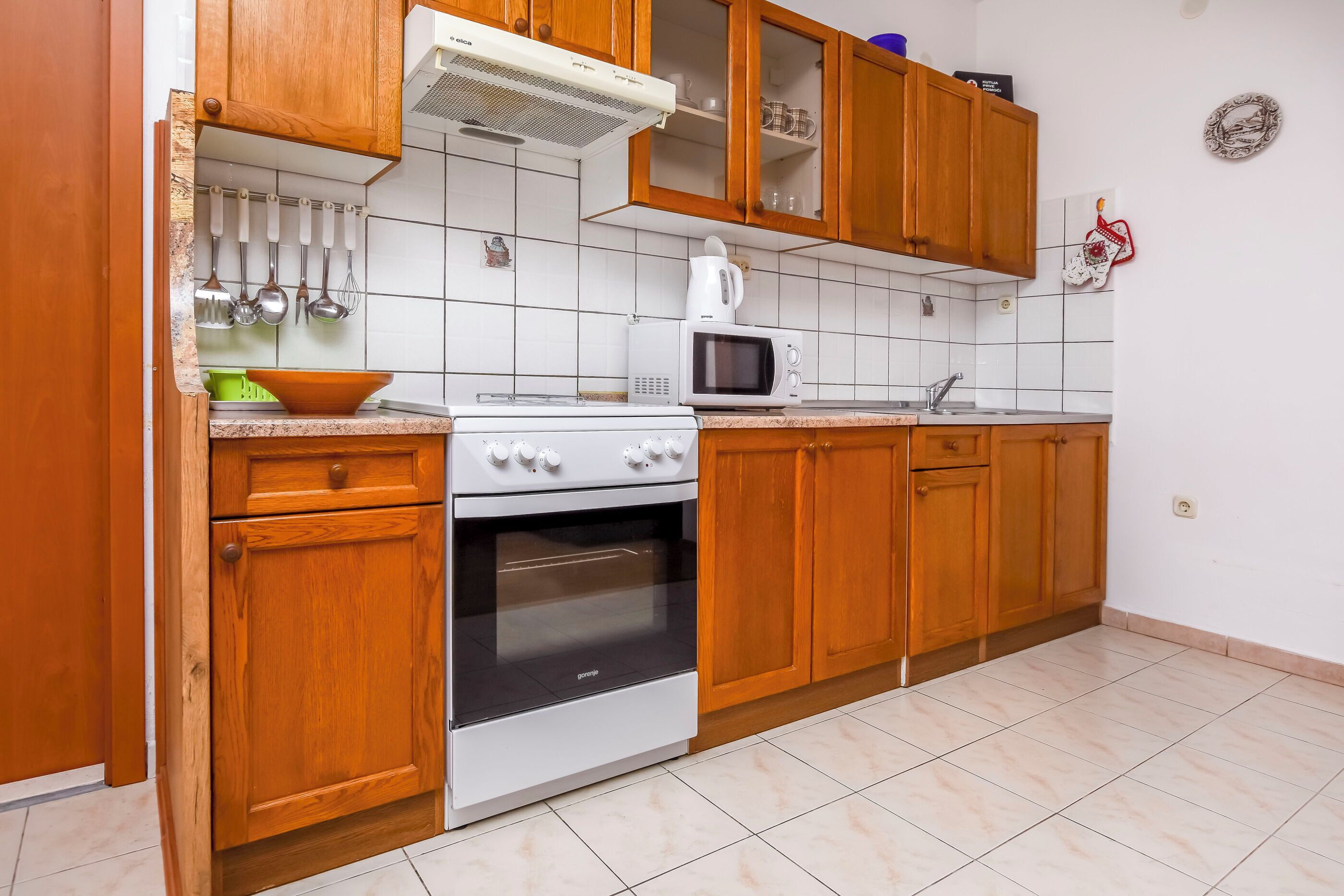 Une cuisine avec des meubles en bois, une cuisinière blanche, un four à micro-ondes et une bouilloire.