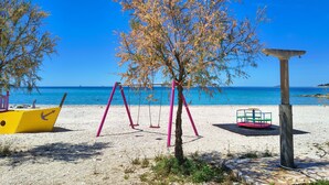 Ein Strand mit Schaukeln, einem gelben Boot und einer Steinstruktur.