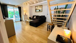 A modern living room with a wooden floor, a black sofa, a white coffee table, and a glass cabinet with plants. -  Viva Villa Village down the Fort  (Gosier)