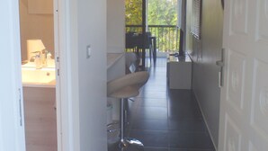A narrow hallway with a bar area, a door labeled "DOME", and a view of a balcony with outdoor scenery.