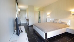A modern bedroom with a large bed, bedside tables, a TV, and a wardrobe.