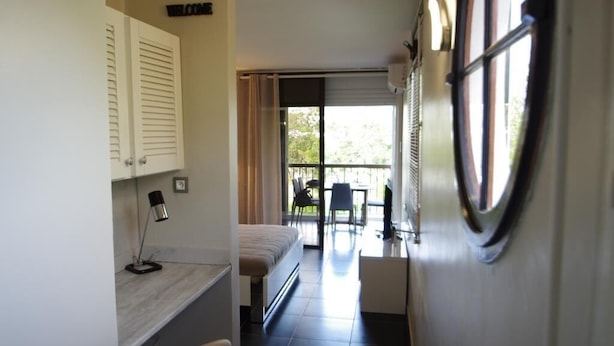 A narrow hallway leading to a balcony with a bed and a desk.