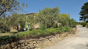 A stone wall with greenery and a building in the background. - Independent villa at the foot of Mt Ventoux (BEDOIN)