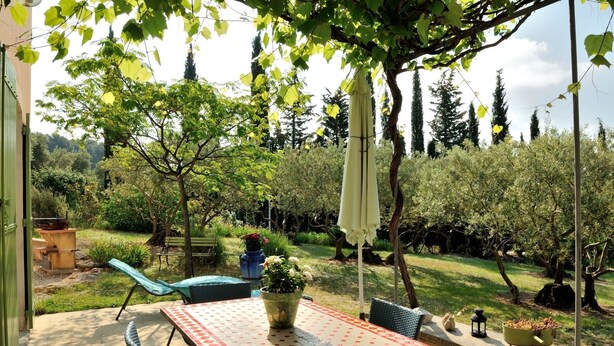 An outdoor patio with a table and chairs, surrounded by greenery and trees. - Independent villa at the foot of Mt Ventoux (BEDOIN)
