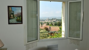 A room with a large window offering a view of a town and greenery. - Independent villa at the foot of Mt Ventoux (BEDOIN)