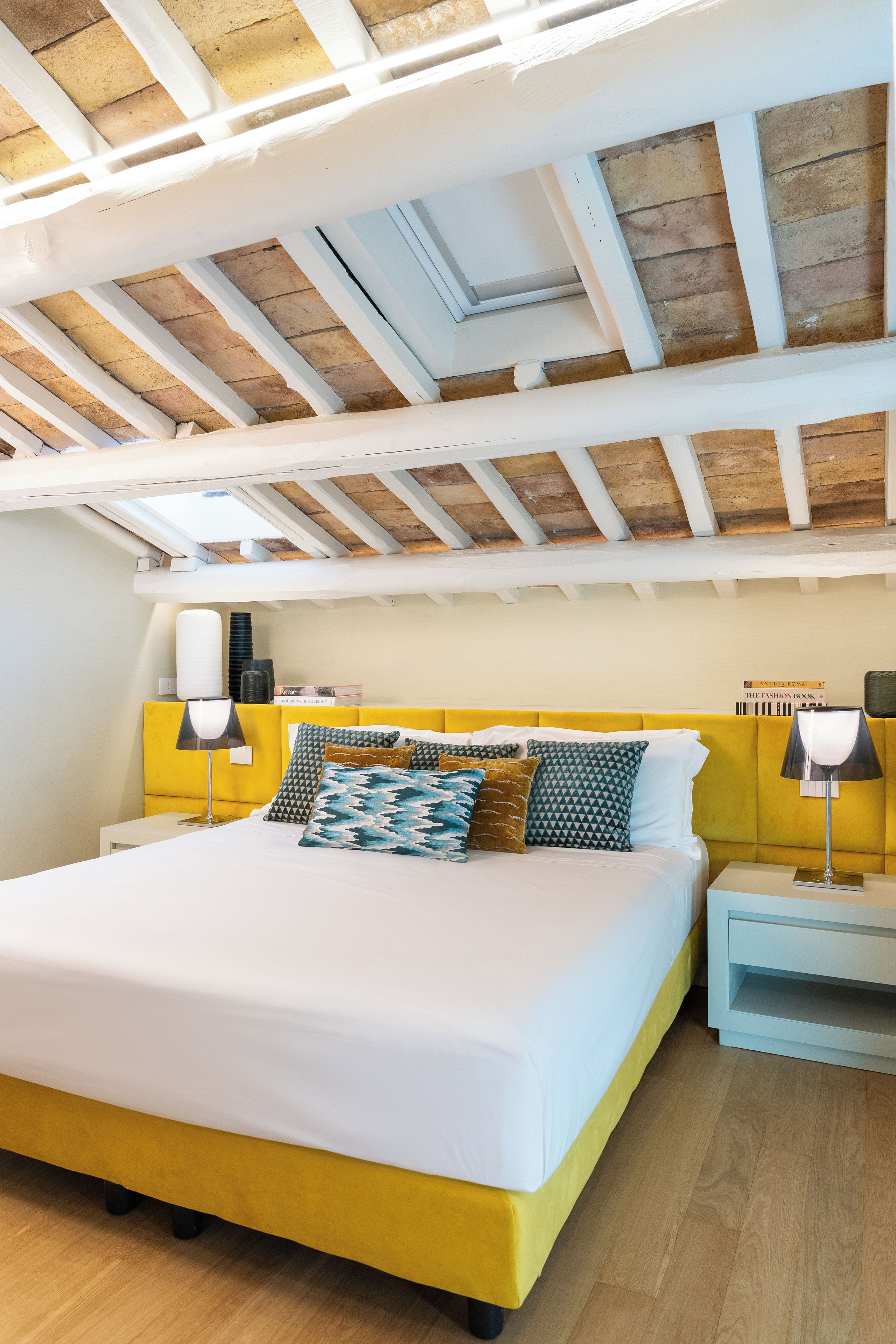 A bedroom with a bed, bedside tables, lamps, and a bookshelf.