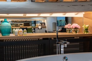 A modern reception area with a wooden counter, a large vase, and a wall-mounted TV. - Laurina 33 (Rome)