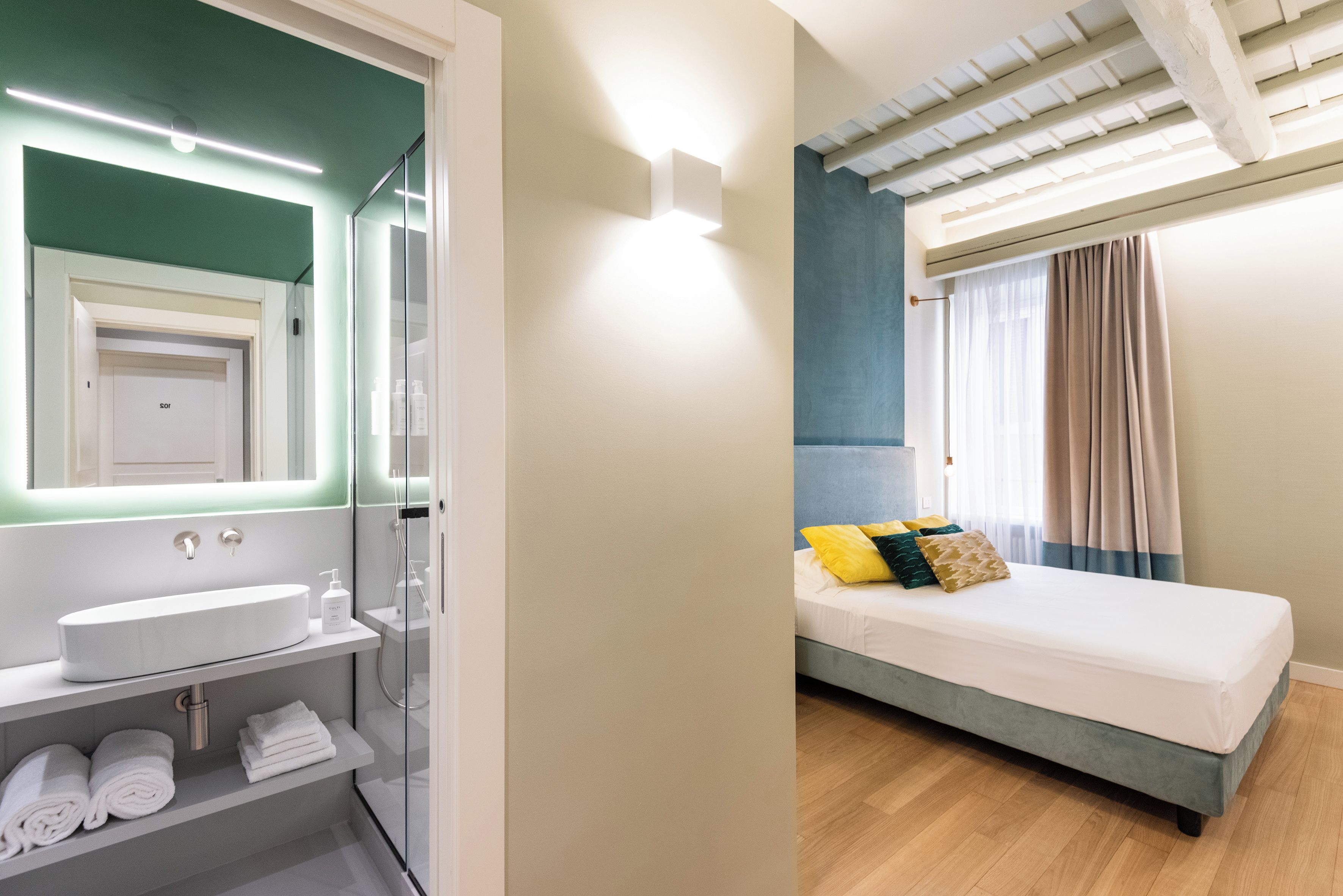 A modern hotel room with a bathroom and a bed.