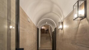 A hallway with a marble floor, a glass door on the left, and a staircase in the background. - Laurina 33 (Rome)