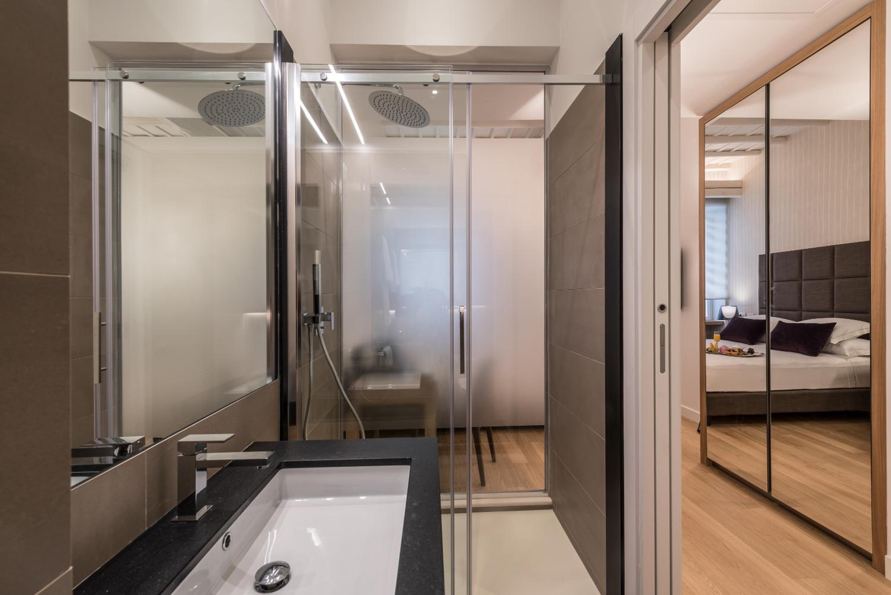 Une salle de bain moderne avec une douche à parois de verre, un meuble-lavabo et un mur miroitant.