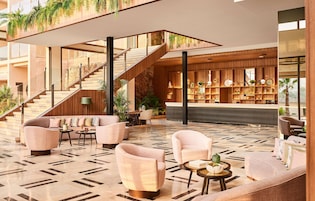 A modern lobby with a staircase, seating area, and a bar.
