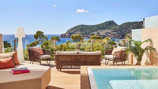 Una terraza con mobiliario exterior, piscina y vistas al mar y a las montañas.
