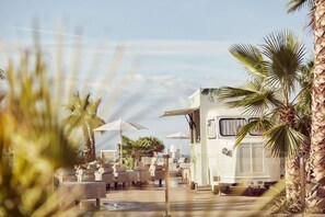 A white RV parked next to a pool area with lounge chairs and umbrellas. - Zafiro Palace Andratx (Andraitx)