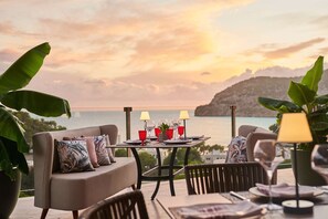 A dining area with a table set for two, overlooking a scenic view of the sea and hills. - Zafiro Palace Andratx (Andraitx)