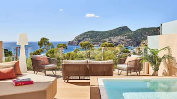 Una terraza con mobiliario exterior, una piscina y vistas al mar y las montañas.
