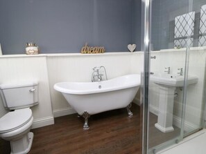 Une salle de bain comprenant une baignoire sur pieds, des toilettes et une douche séparée par des parois en verre.