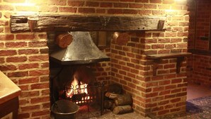 Une cheminée en briques avec une hotte en métal et des bûches.