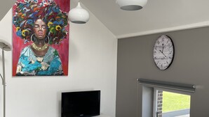 Moderni olohuone, jossa on litteänäyttöinen televisio, lasinen sohvapöytä ja suuri abstrakti taulu.