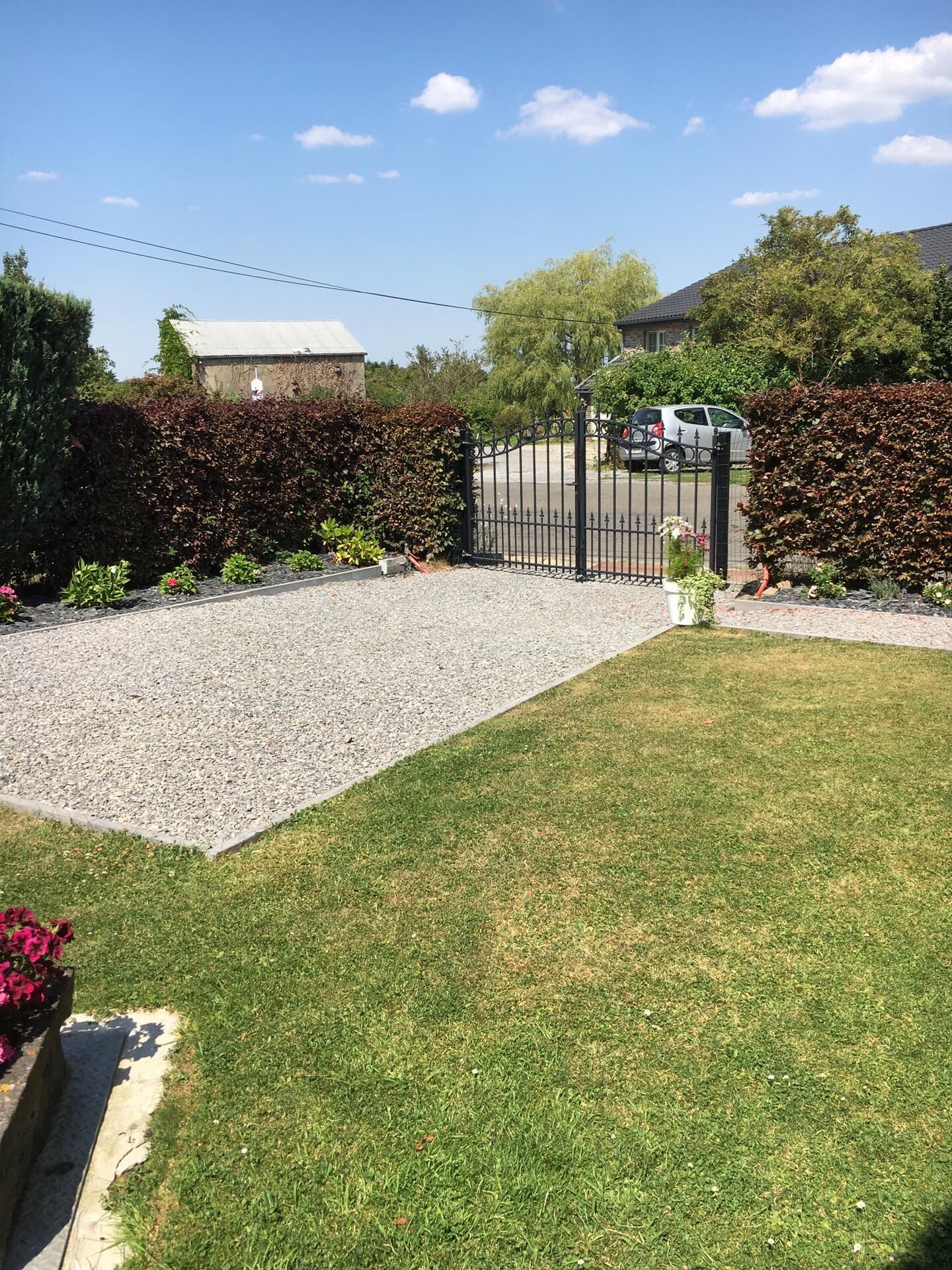 A residential driveway with a gravel path leading to a gated entrance.