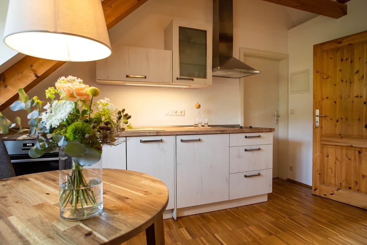 Eine moderne Küche mit weißen Schränken, einer Holzausziehtheke und einem Blumenstrauß auf einem Holztisch.