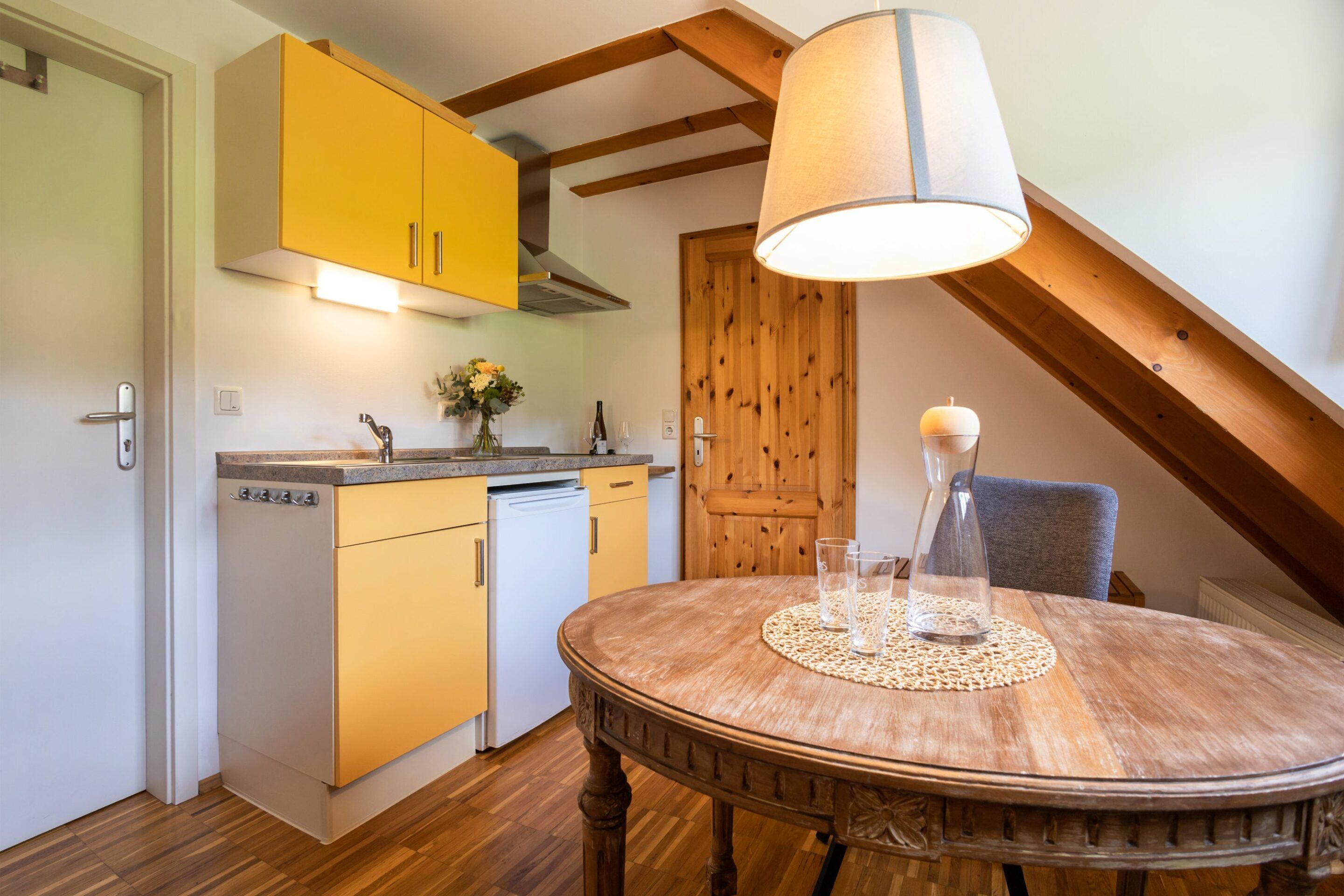 A kitchen with yellow cabinets, a wooden ceiling, and a dining table with a placemat.