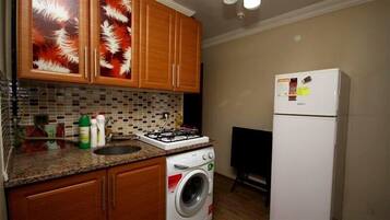 Een koelkast/vriezer, een kookplaat, kookgerei, borden en bestek