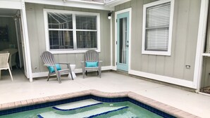 A small outdoor swimming pool with blue tiles, two grey chairs with blue cushions, and a white door. - Tranquil private pool home near Siesta Key Beach
 (Sarasota)