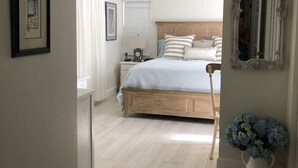 A bedroom with a wooden bed, a nightstand, a mirror, and a vase of flowers. - Tranquil private pool home near Siesta Key Beach
 (Sarasota)