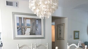 A dining area with a white table and chairs, a large framed picture on the wall, and a decorative ceiling light. - Tranquil private pool home near Siesta Key Beach
 (Sarasota)