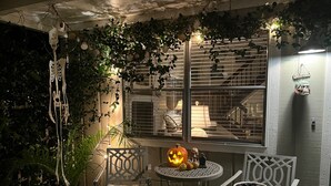 A cozy patio area with a table and chairs, a decorative pumpkin, and a skull figure. - Tranquil private pool home near Siesta Key Beach
 (Sarasota)