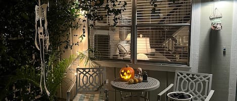 A cozy patio area with a table and chairs, a decorative pumpkin, and a skull figure.