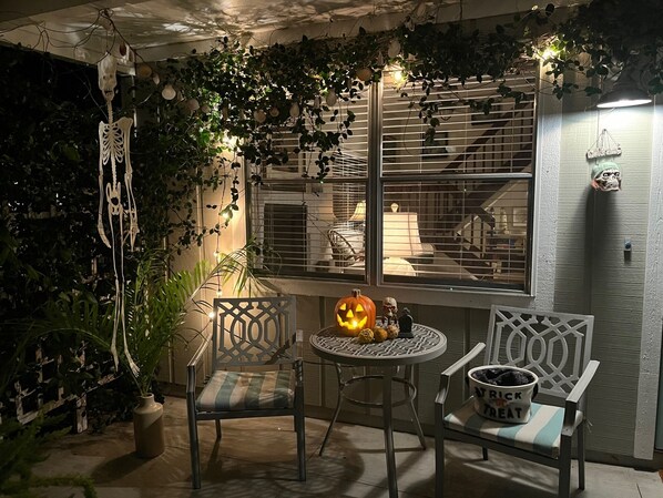 A cozy patio area with a table and chairs, a decorative pumpkin, and a skull figure.