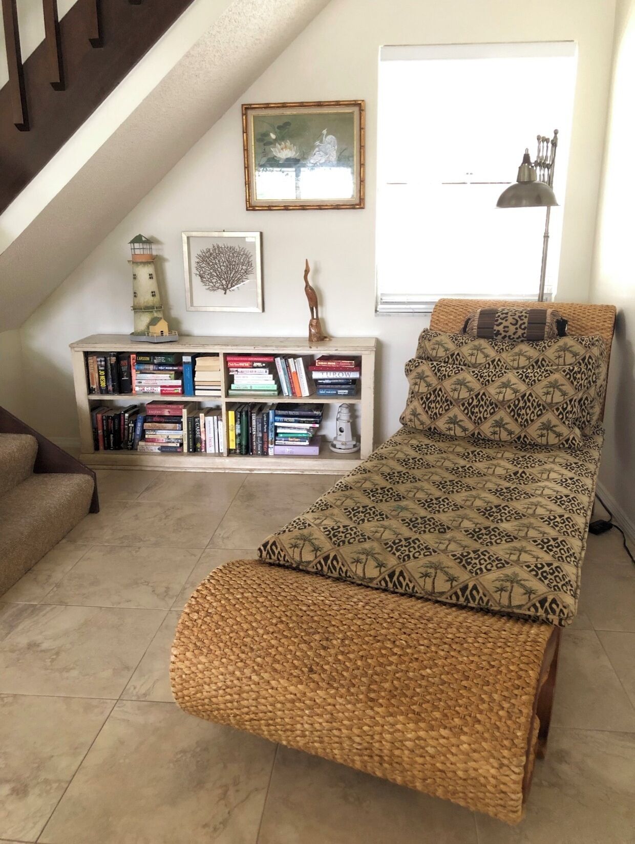 Un dormitorio estilo loft acogedor con techo inclinado, una estantería, una cama estampada y una lámpara pequeña.