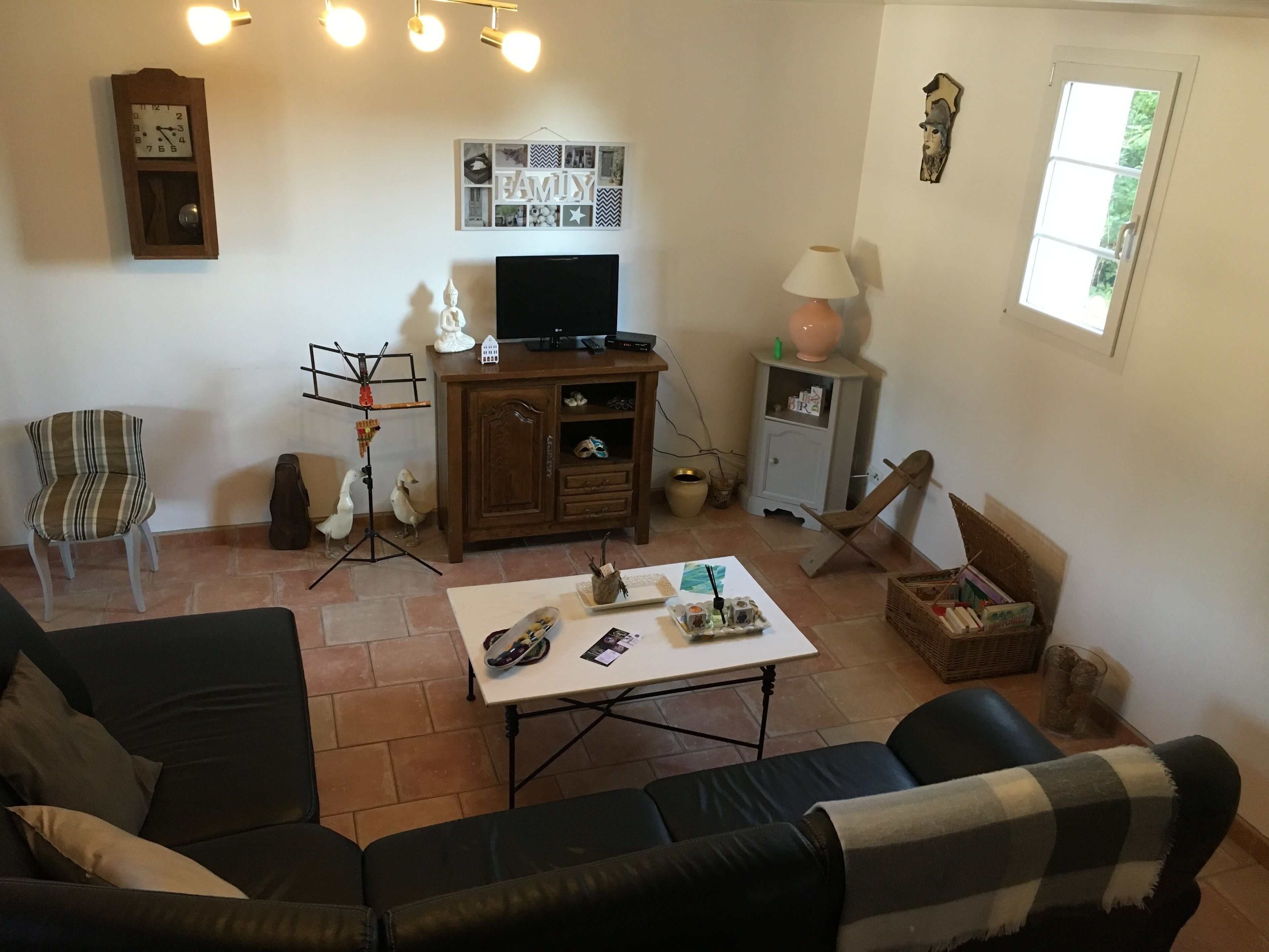 A living room with a sofa, a coffee table, a TV, a clock, and a wall with a 'FAMILY' sign.