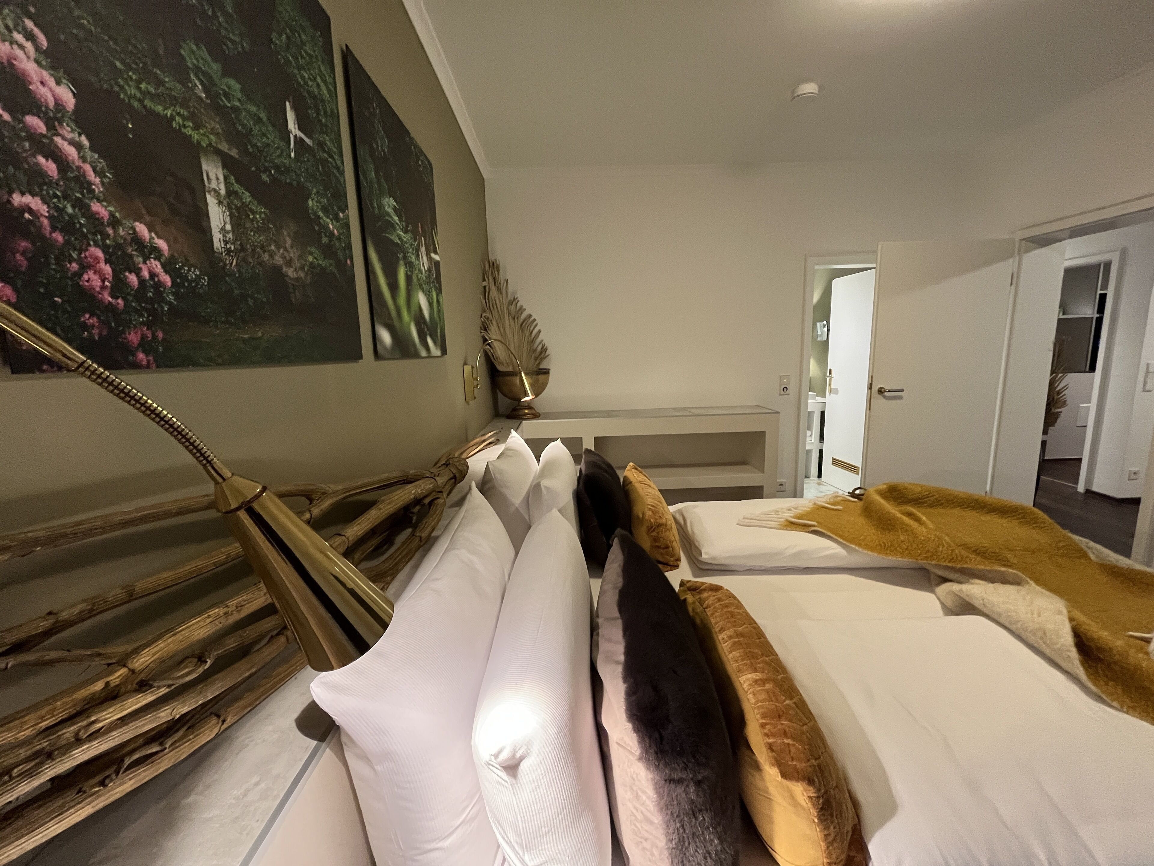A hotel room with a bed, a nightstand, a lamp, and a painting on the wall.