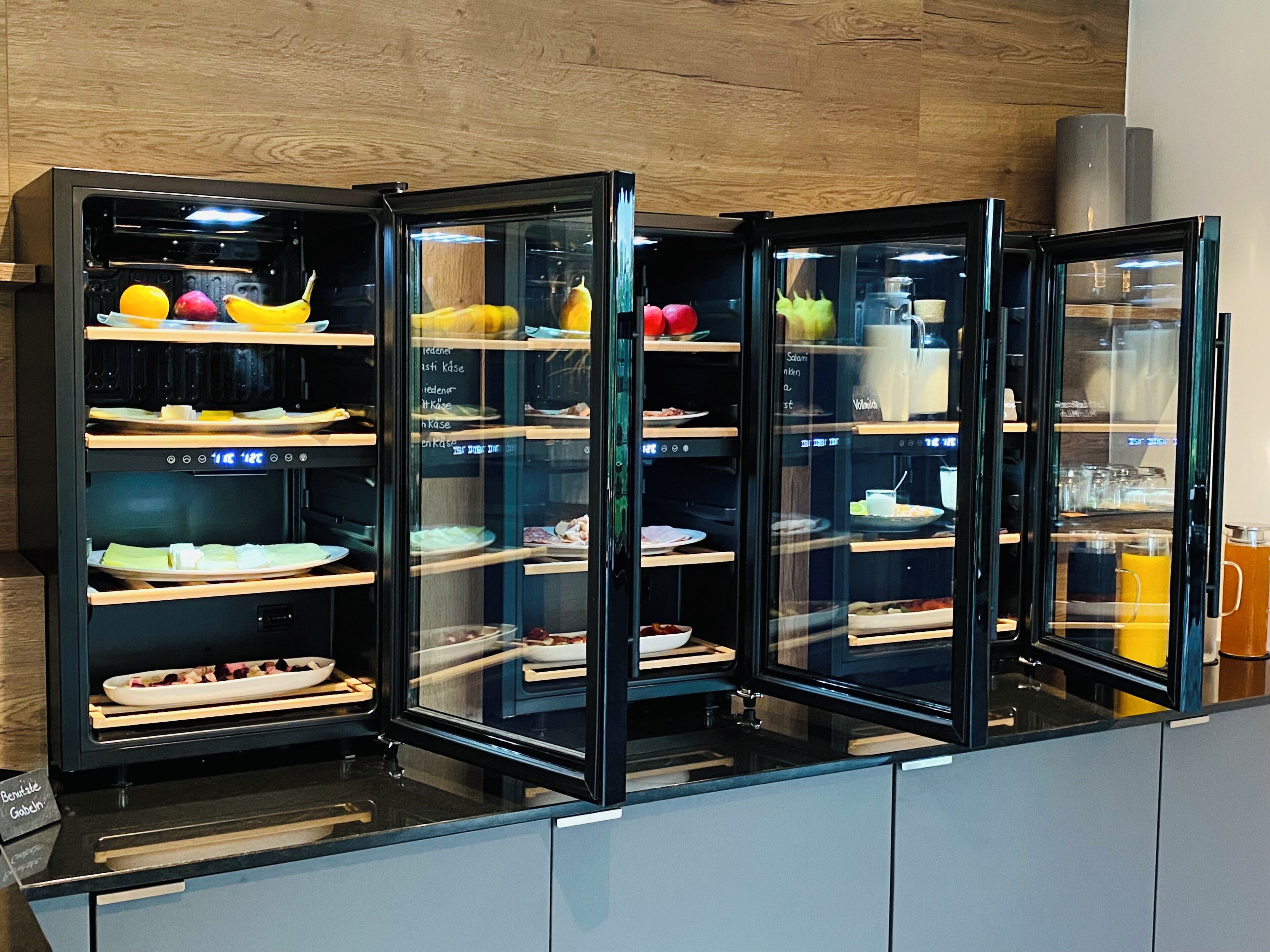 A kitchen with a black countertop and a glass display case containing various food items.