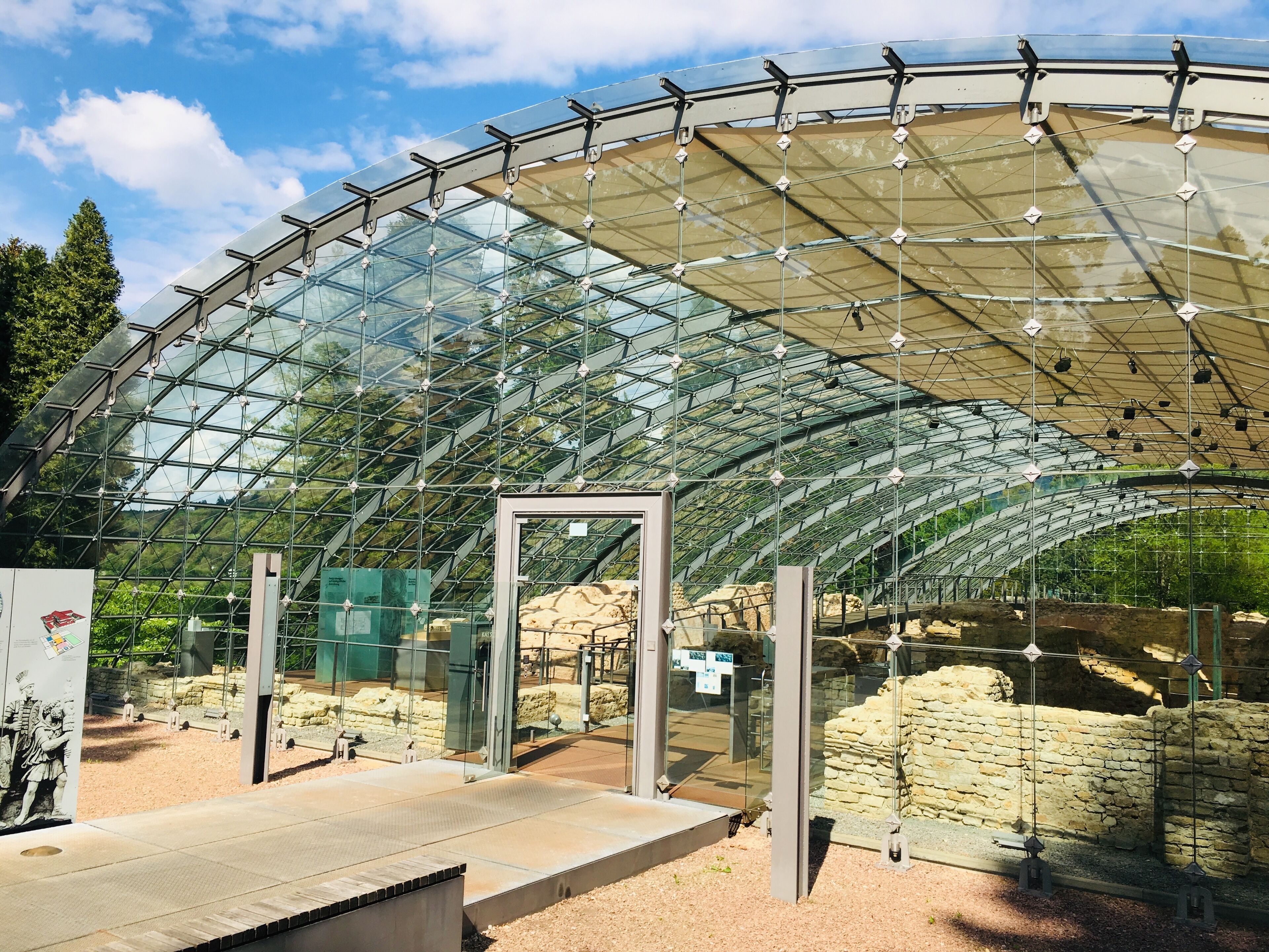 Une structure entièrement vitrée, dotée d’un toit incurvé, de murs en pierre et d’un sol en gravier.