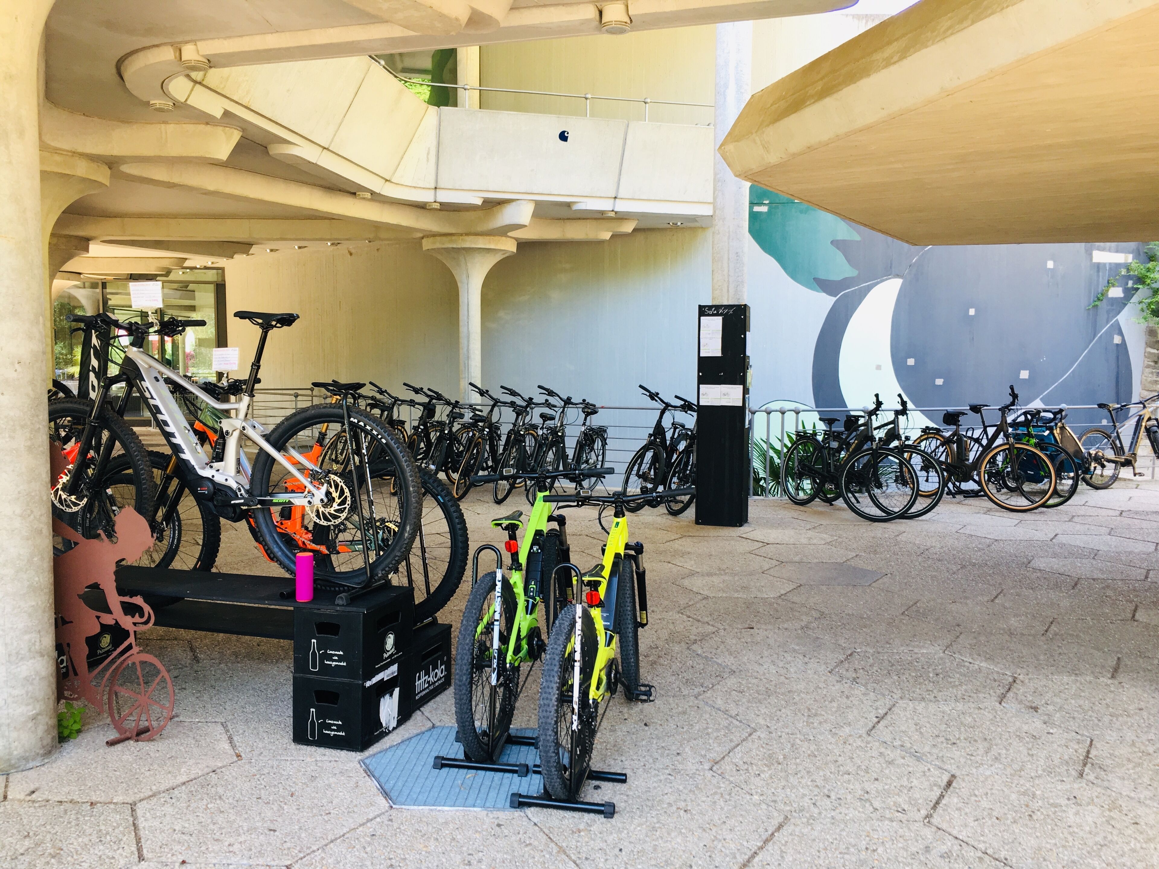 A bike parking area with multiple bicycles, a bike stand, and a ticket machine.