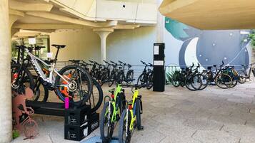 A bike parking area with multiple bicycles, a bike stand, and a ticket machine.