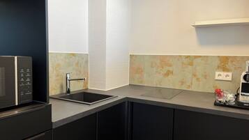A modern kitchen with a built-in microwave, a stainless steel sink, and a coffee machine.