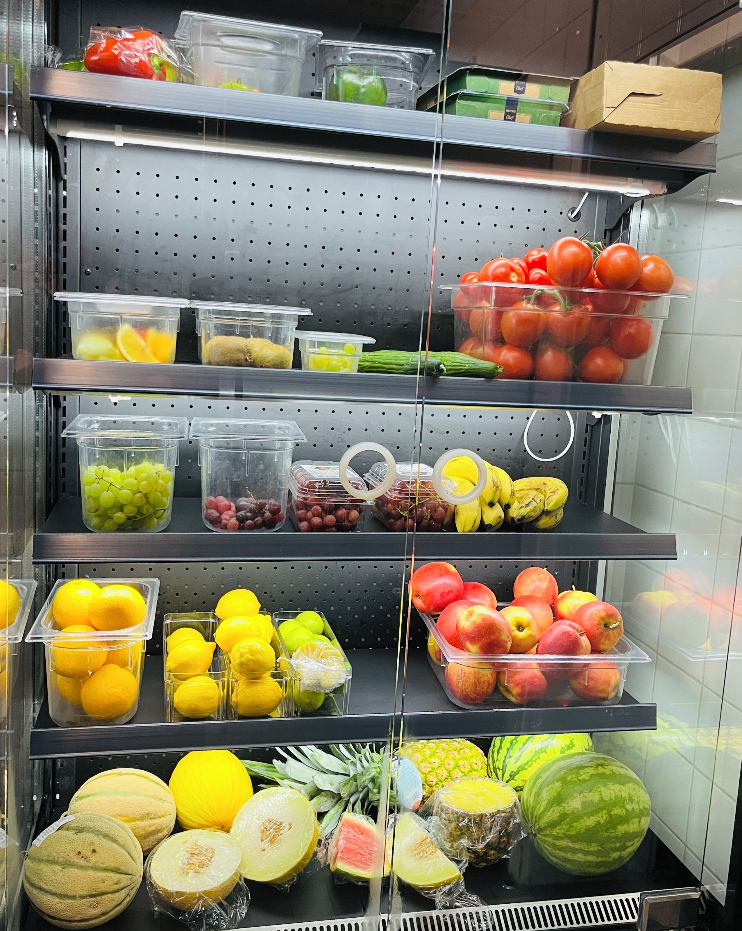 A refrigerated display of various fruits and vegetables in a grocery store.