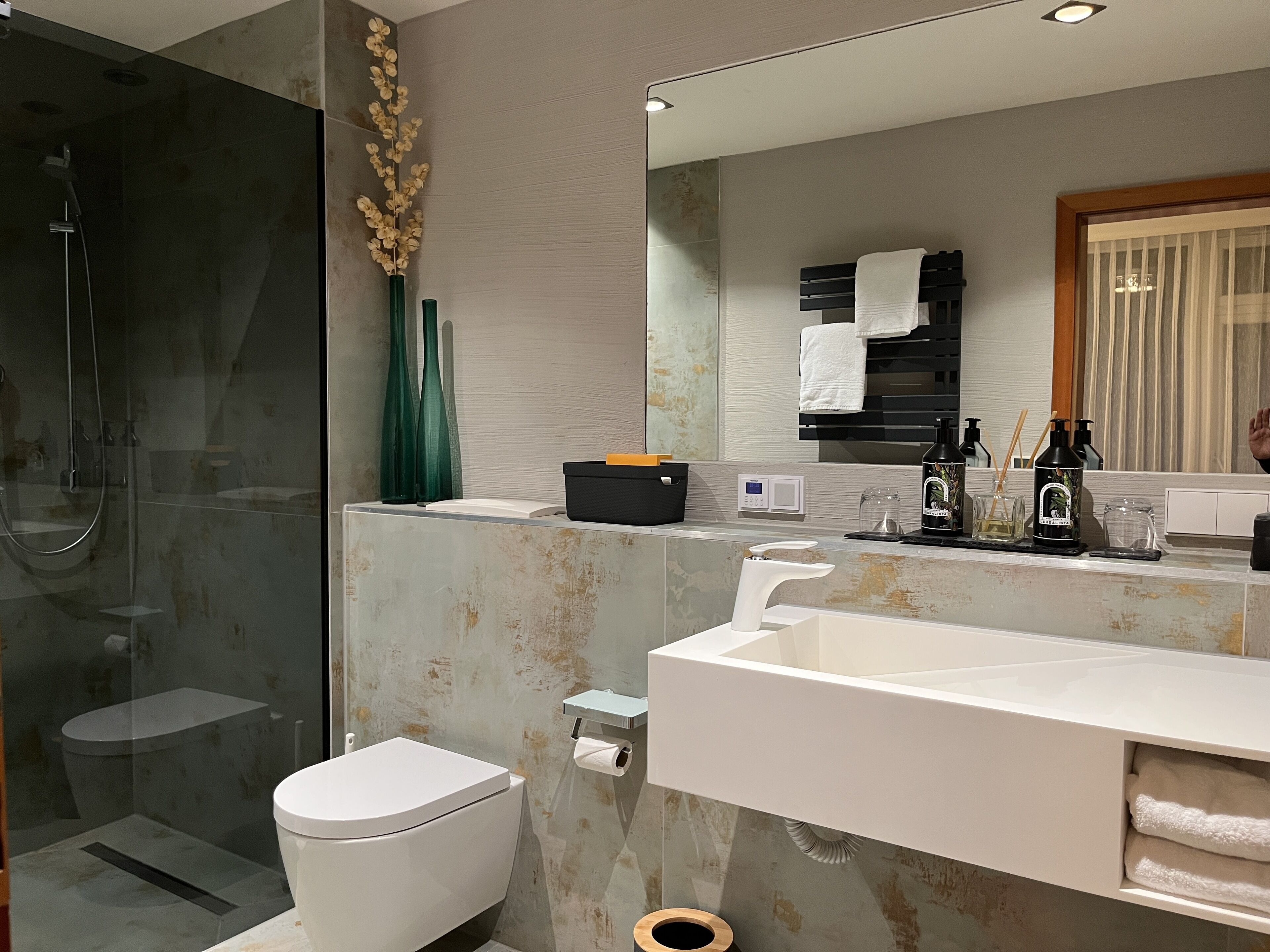 A modern bathroom with a glass-enclosed shower, a white toilet, and a large vanity with a mirror.
