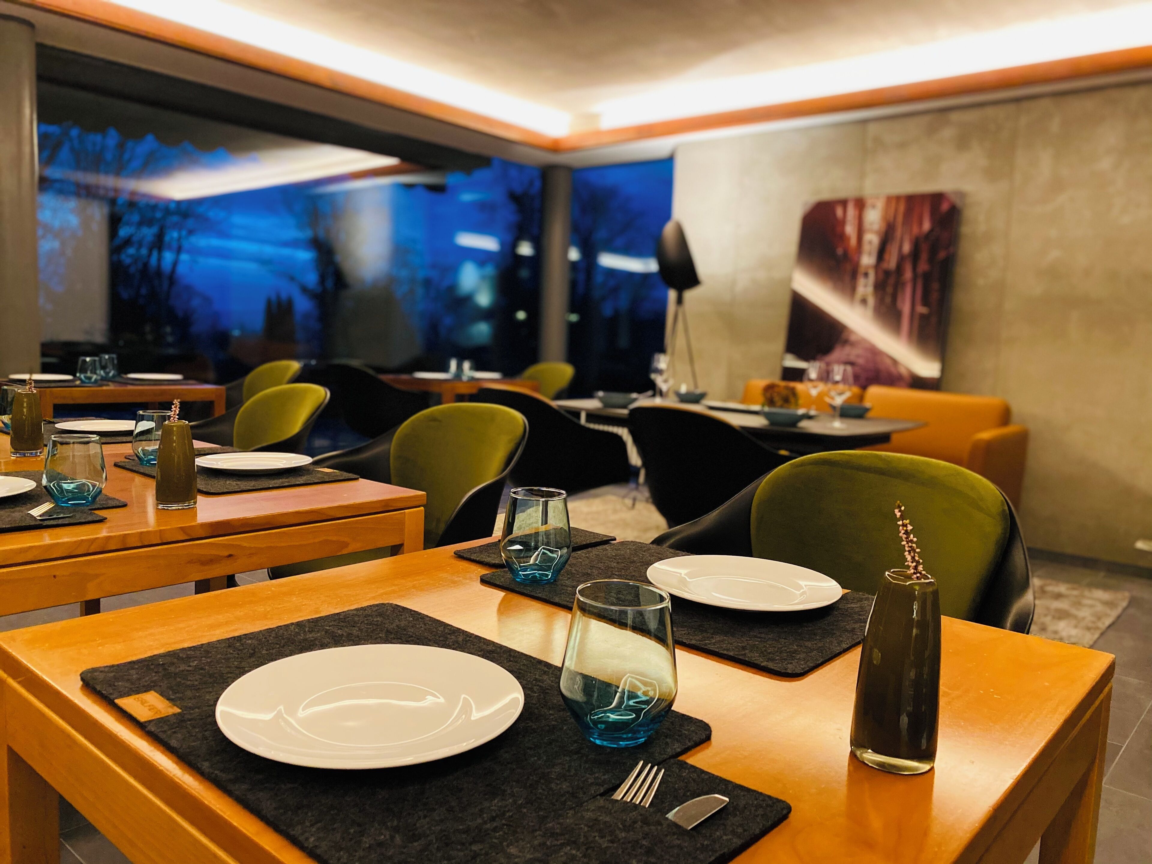 Ein Restaurant mit gedeckten Tischen, Stühlen und einem großen Fenster mit Blick.