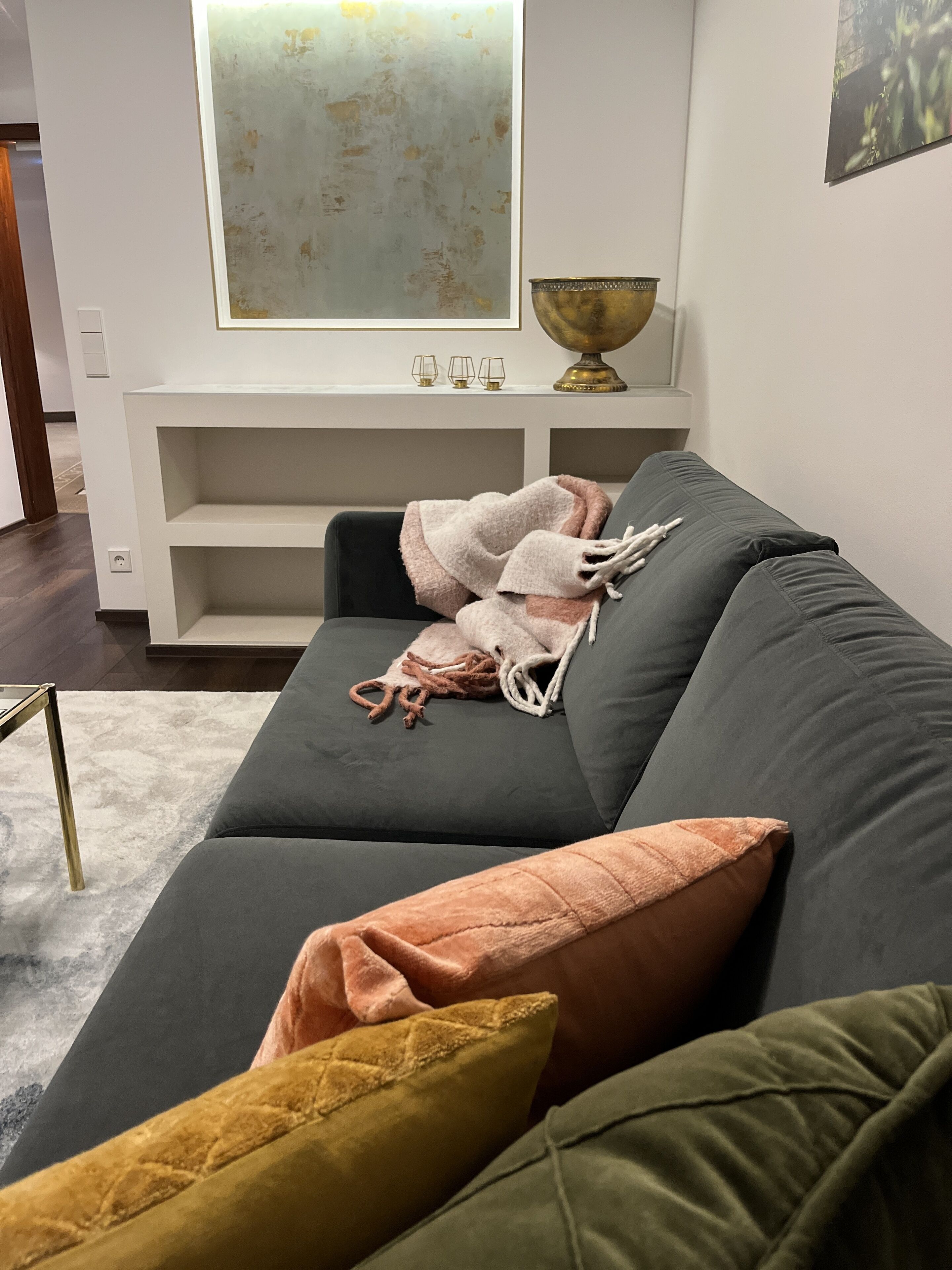 A modern living room with a grey sofa, a white console table, and a large abstract painting above it.
