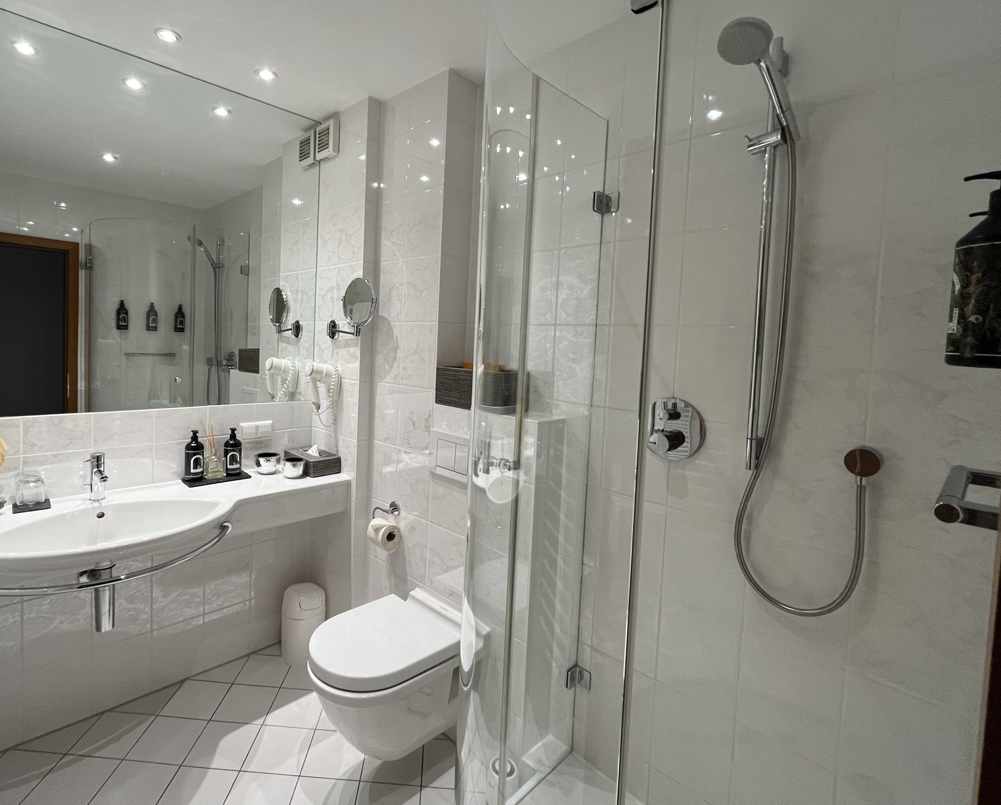Un baño moderno con ducha de vidrio, lavabo blanco y retrete.