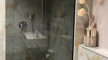 Un baño moderno con ducha envuelta en vidrio, un inodoro y un tocador con un jarrón decorativo.
