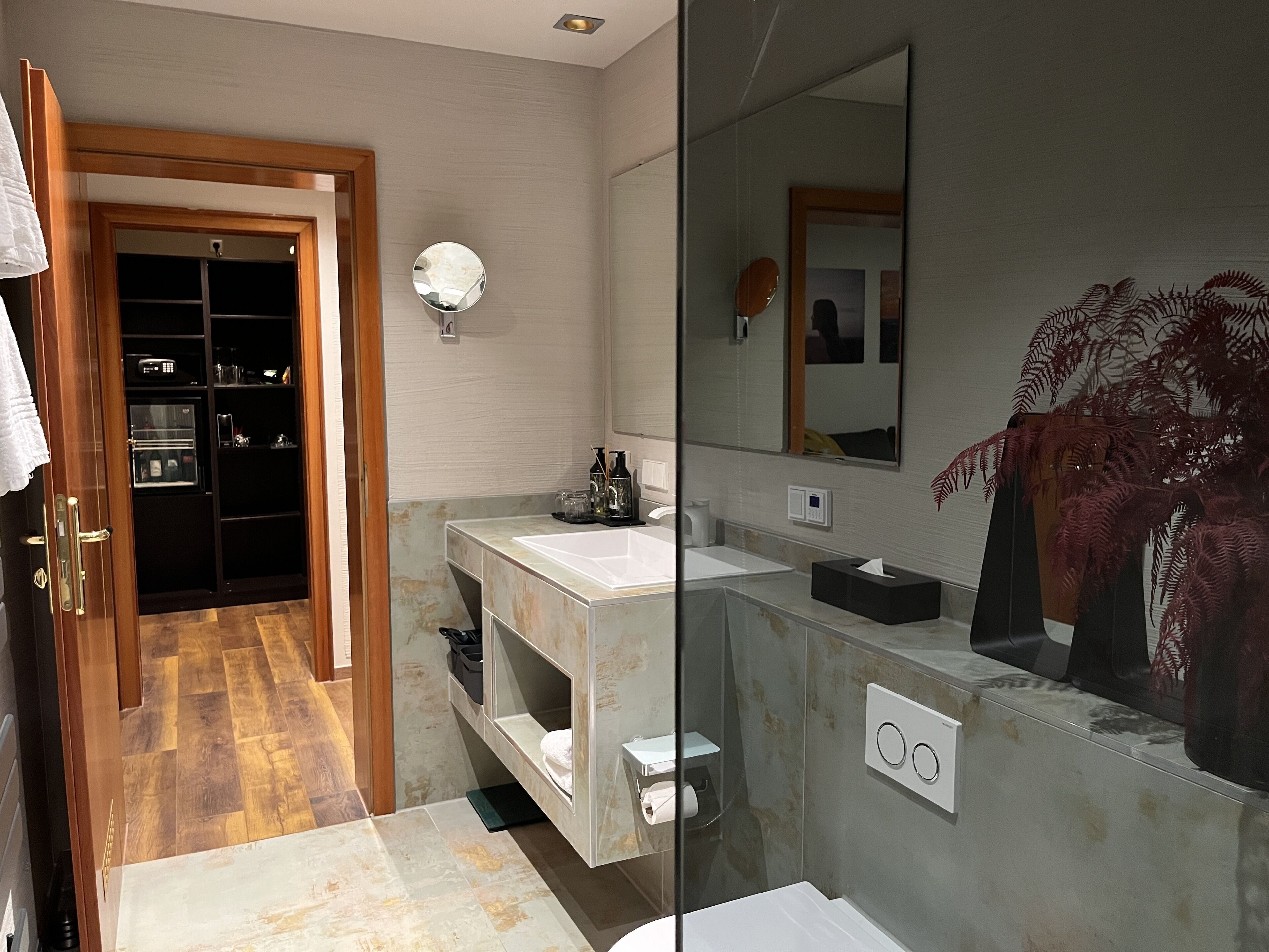 A modern bathroom with a glass shower enclosure, a white sink, and a large mirror.