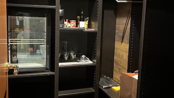 Ein begehbarer Kleiderschrank mit Regalen, einer Kleiderstange und einem kleinen Kühlschrank.